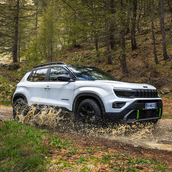 Jeep Avenger 4xe Hybrid білого кольору їде через калюжу у лісі