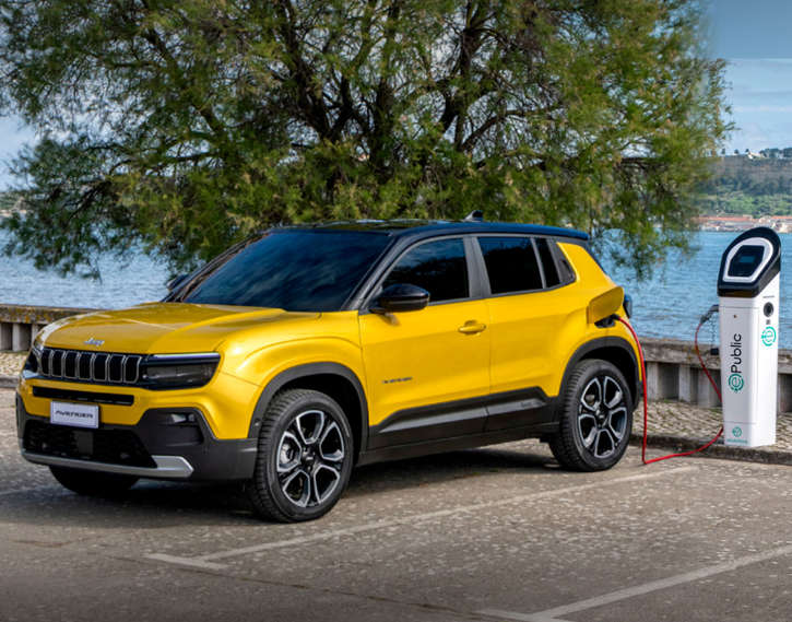 Jeep Avenger Electric жовтого кольору заряджається на стоянці біля моря